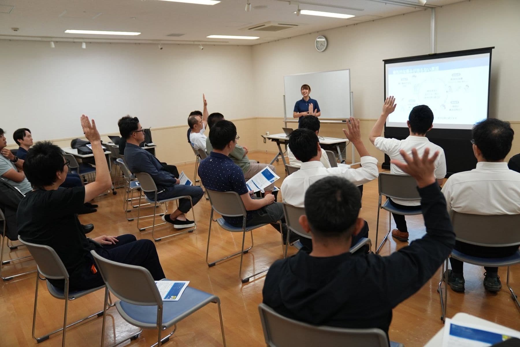 小田原二世会の講演会で、参加者が手を挙げながら講師の話を聞く様子